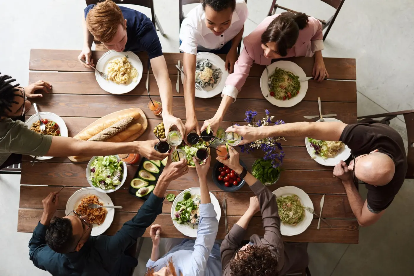 Friends sharing a meal around a wooden table, seen from above